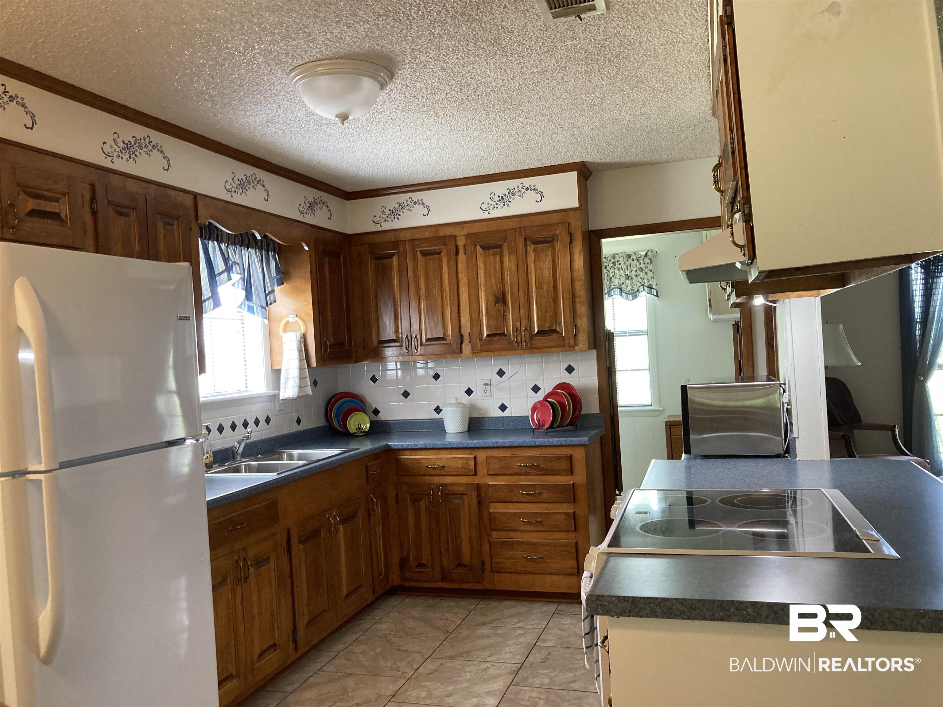 6151 Meadows Road Walnut Hill, FL 32568 - Photo 10 of 29 Kitchen with decorative backsplash, a wealth of natural light, sink, and white fridge
