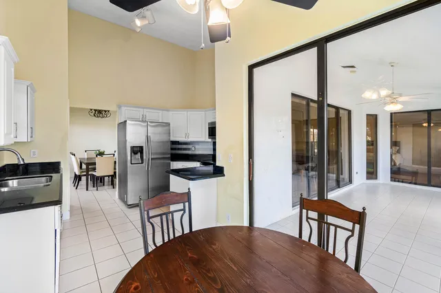 a kitchen with stainless steel appliances granite countertop a refrigerator a stove a sink a dining table and chairs with wooden floor