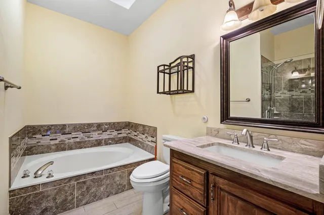 a bathroom with a granite countertop sink and a bathtub