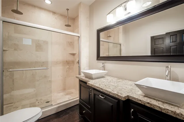 a bathroom with a granite countertop sink a mirror and a shower