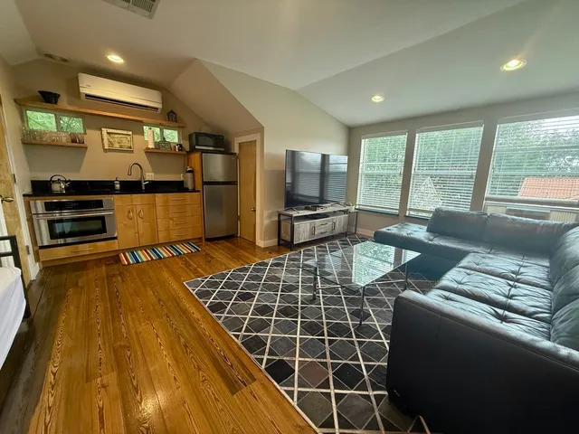 a living room with furniture a large window with kitchen view
