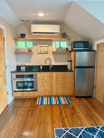 a kitchen with stainless steel appliances wooden floor and window
