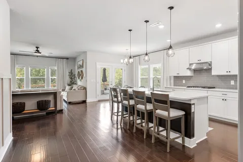 a open kitchen with stainless steel appliances granite countertop a stove a refrigerator a kitchen island a dining table and chairs with wooden floor