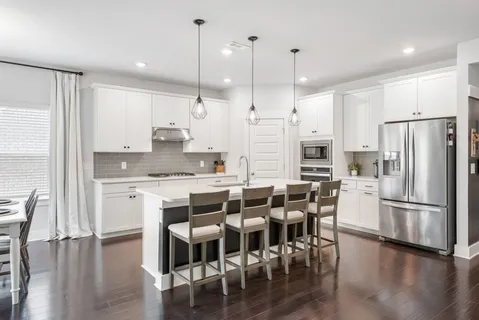 a kitchen with stainless steel appliances granite countertop a dining table chairs stove refrigerator and wooden floor