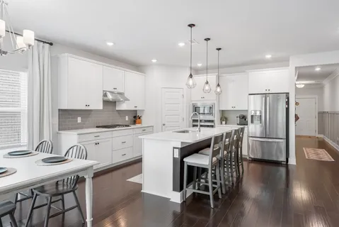 a kitchen with stainless steel appliances granite countertop a dining table chairs stove refrigerator and cabinets