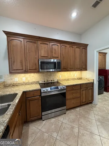 a kitchen with stainless steel appliances granite countertop a stove sink and cabinets