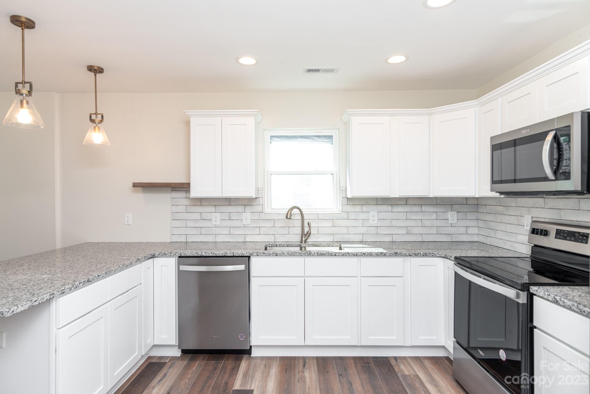 693 Gibson Drive Northwest Concord, NC 28025 - Photo 4 of 12 a kitchen with a sink a stove a microwave and cabinets