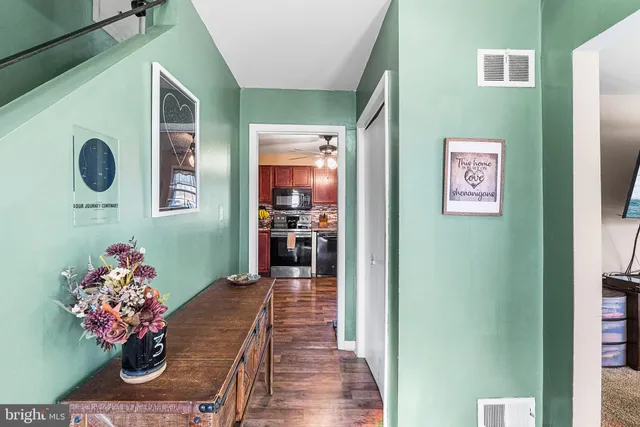 a hallway with painting on the wall and a potted plant