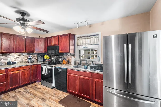 a kitchen with stainless steel appliances granite countertop a refrigerator a sink dishwasher a stove and white cabinets