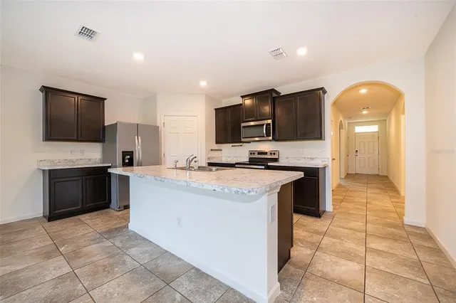 a large kitchen with stainless steel appliances kitchen island granite countertop a sink and cabinets