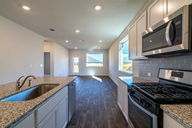 a kitchen with granite countertop a sink a stove and cabinets