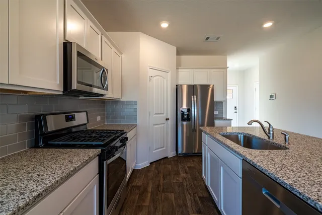 a kitchen with stainless steel appliances granite countertop a sink stove and refrigerator