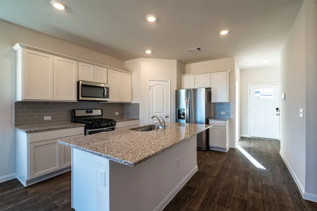 a kitchen with stainless steel appliances granite countertop a sink stove microwave and refrigerator