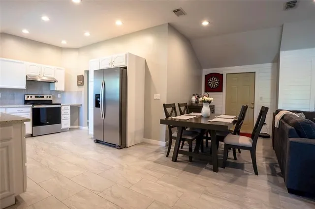 a kitchen with kitchen island a dining table chairs stainless steel appliances and cabinets