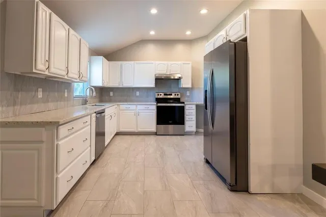 a large kitchen with stainless steel appliances granite countertop a refrigerator and a stove top oven