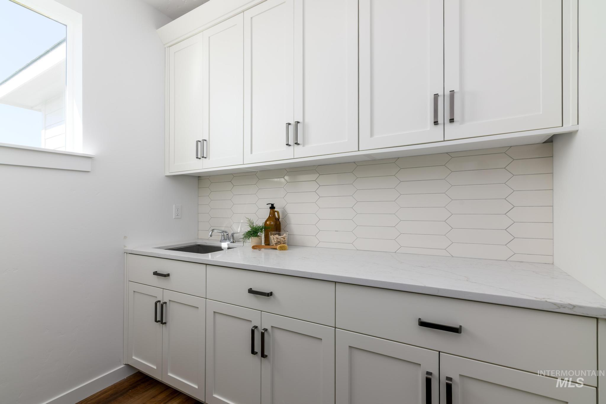 6049 West Snow Currant Street Meridian, ID 83646 - Photo 11 of 12 Bar area featuring decorative backsplash, light stone counters, white cabinetry, and dark wood-style floors