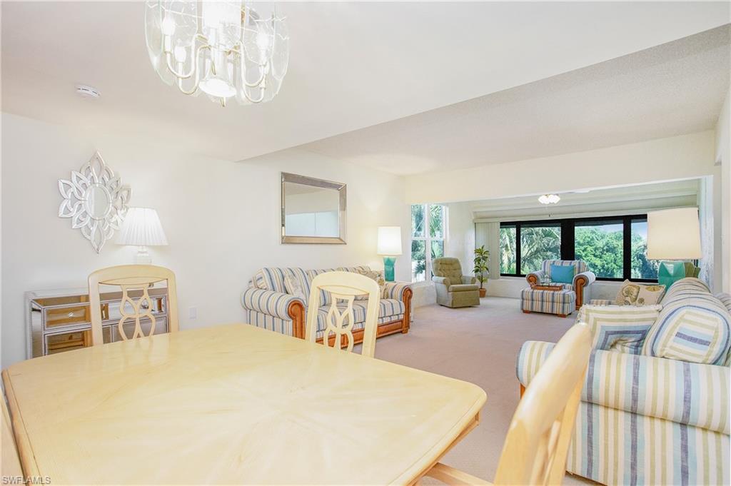 955 Palm View Drive, Unit B307 Naples, FL 34110 - Photo 11 of 25 a spacious bedroom with a bed and a chandelier