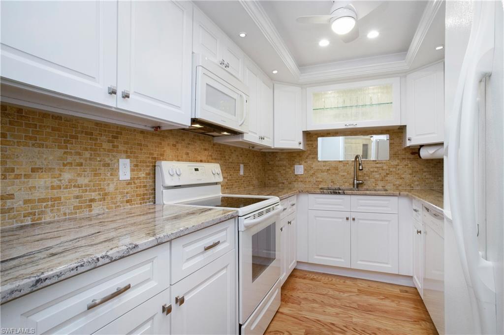 955 Palm View Drive, Unit B307 Naples, FL 34110 - Photo 12 of 25 a kitchen with granite countertop white cabinets and white appliances