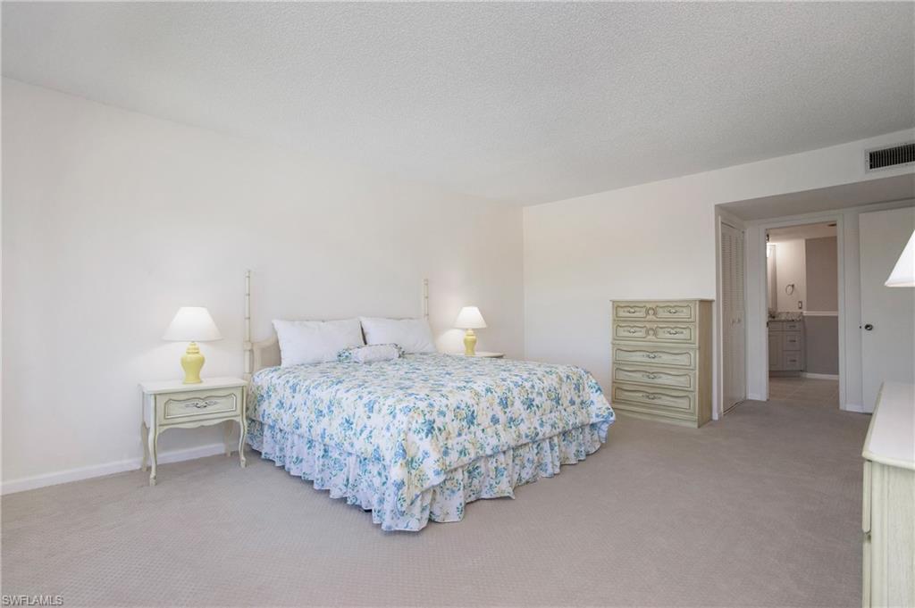 955 Palm View Drive, Unit B307 Naples, FL 34110 - Photo 16 of 25 a bedroom with a bed and a lamp