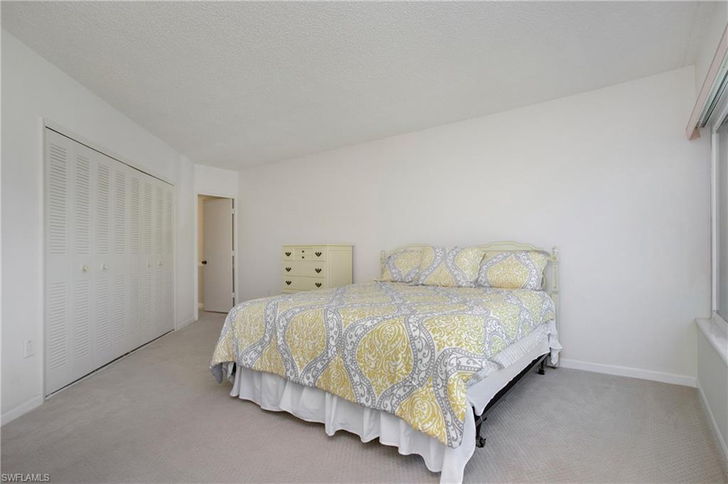 955 Palm View Drive, Unit B307 Naples, FL 34110 - Photo 21 of 25 a bedroom with a bed and a night stand