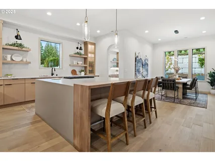 a kitchen with stainless steel appliances kitchen island granite countertop a table chairs sink and wooden cabinets