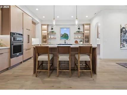 a kitchen with kitchen island a dining table chairs stainless steel appliances and cabinets