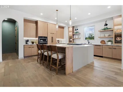 a kitchen with stainless steel appliances kitchen island granite countertop a table chairs sink and cabinets