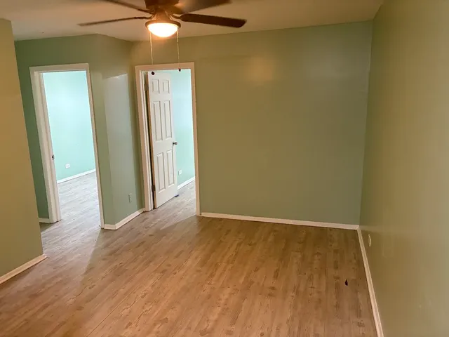 an empty room with wooden floor and fan