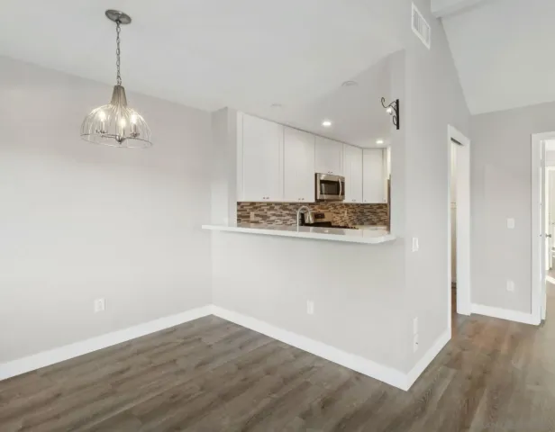 a kitchen with a table a refrigerator and wooden floor