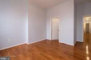 a view of an empty room with wooden floor and closet