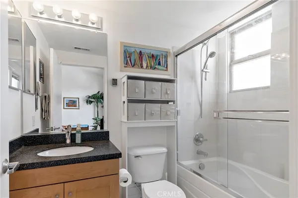 a bathroom with a granite countertop sink toilet and shower