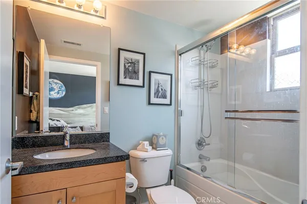 a bathroom with a granite countertop sink toilet a mirror and shower