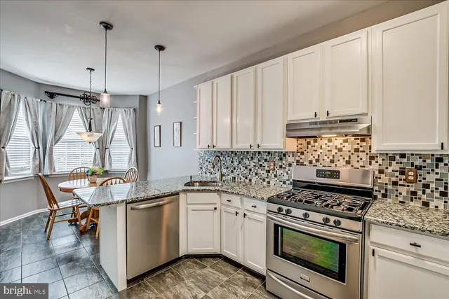a kitchen with granite countertop a sink stove and white cabinets