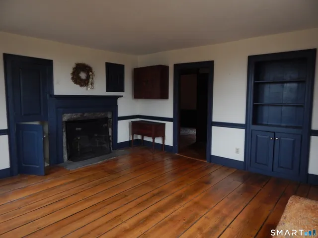 a view of an empty room with wooden floor and a fireplace