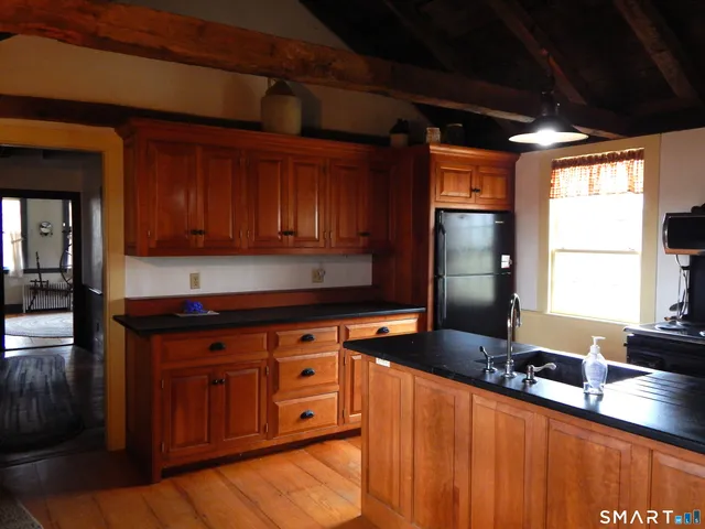 a kitchen with stainless steel appliances granite countertop a refrigerator a sink dishwasher a stove and white countertops with wooden floor