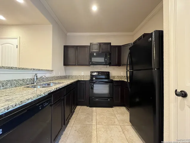 a kitchen with granite countertop a refrigerator and a stove top oven