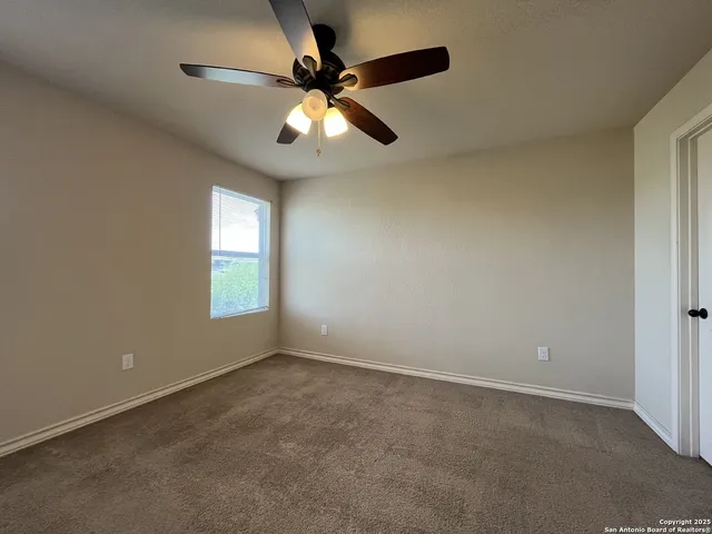 an empty room with a window and a fan