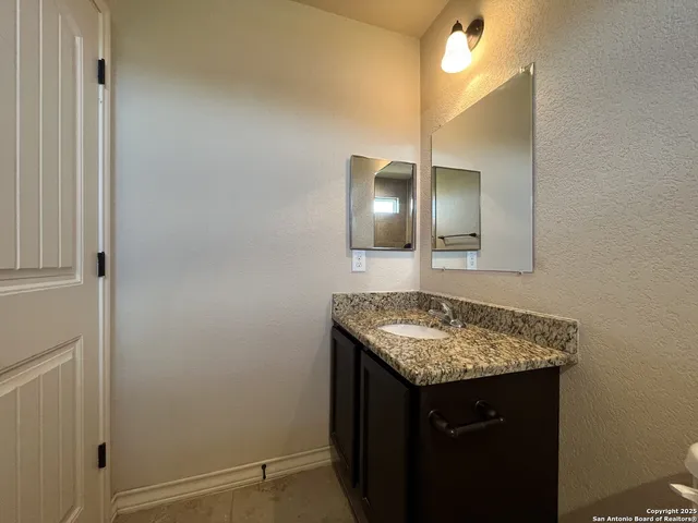 a bathroom with a granite countertop sink and a mirror