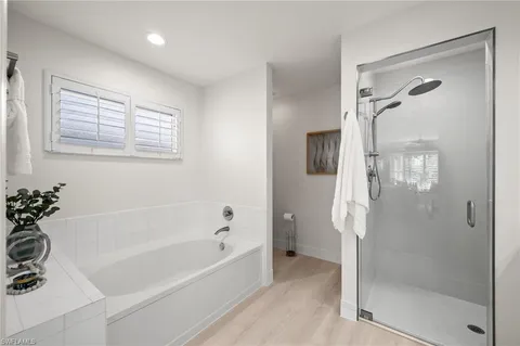 a bathroom with a bathtub a shower and a mirror