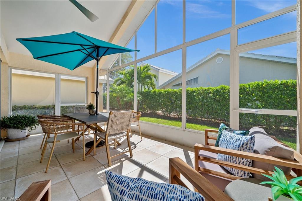 1590 Weybridge Circle, Unit 52 Naples, FL 34110 - Photo 30 of 36 a view of a patio with couches table and chairs under an umbrella