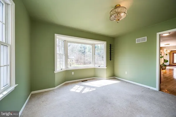 an empty room with chandelier fan and windows