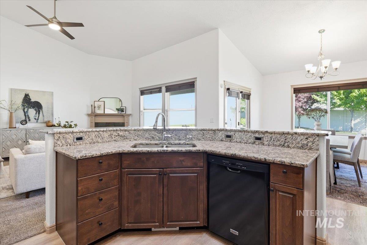 1183 North Buffalo Way Middleton, ID 83644 - Photo 13 of 47 Kitchen island featuring granite-style countertops, an undermount sink with a gooseneck faucet, integrated dark wood-finish cabinetry, and a built-in dishwasher