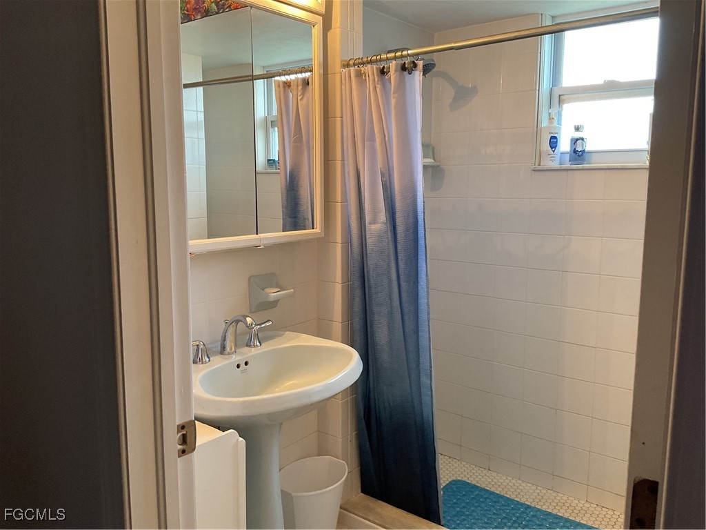 1002 Michael Avenue Lehigh Acres, FL 33936 - Photo 29 of 34 a bathroom with a sink a mirror a toilet and shower