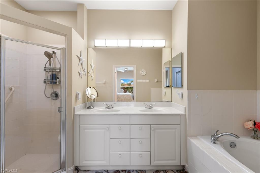 8140 Chancel Court, Unit 2 Naples, FL 34104 - Photo 15 of 39 Bathroom featuring double vanity, a stall shower, and a garden tub