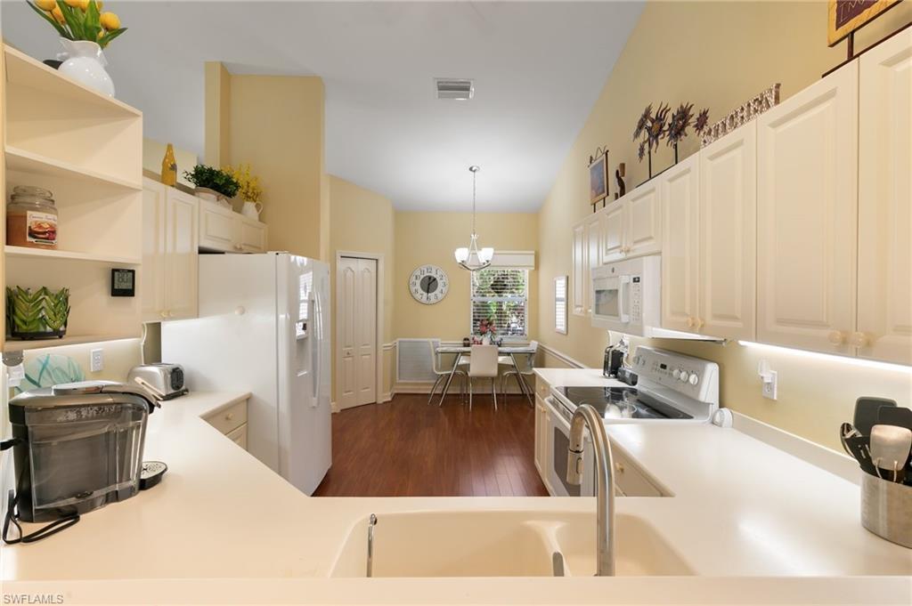 8140 Chancel Court, Unit 2 Naples, FL 34104 - Photo 6 of 39 Kitchen with white appliances, dark wood-style floors, open shelves, light countertops, and vaulted ceiling