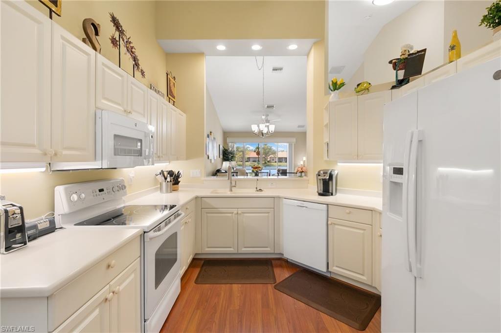 8140 Chancel Court, Unit 2 Naples, FL 34104 - Photo 7 of 39 Kitchen with white appliances, light countertops, white cabinetry, dark wood-style flooring, and vaulted ceiling