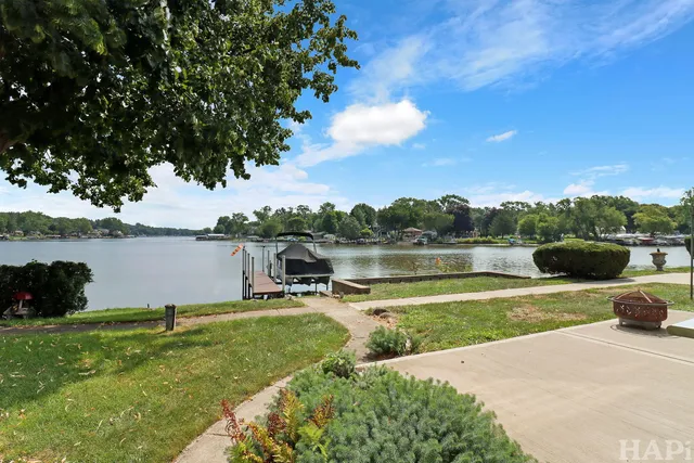 a view of a lake with a yard and a large tree