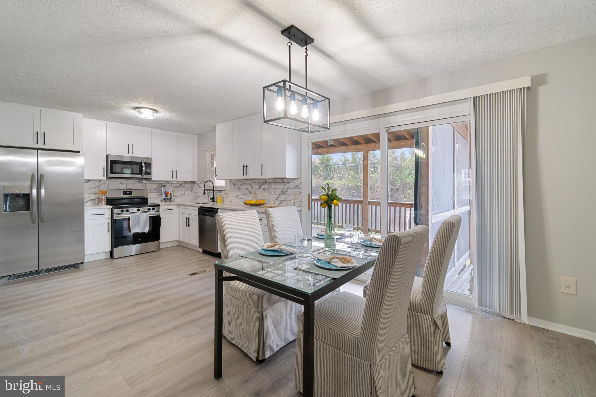 8546 Skipjack Place Pasadena, MD 21122 - Photo 2 of 20 a kitchen with stainless steel appliances granite countertop a refrigerator a stove top oven a dining table and chairs