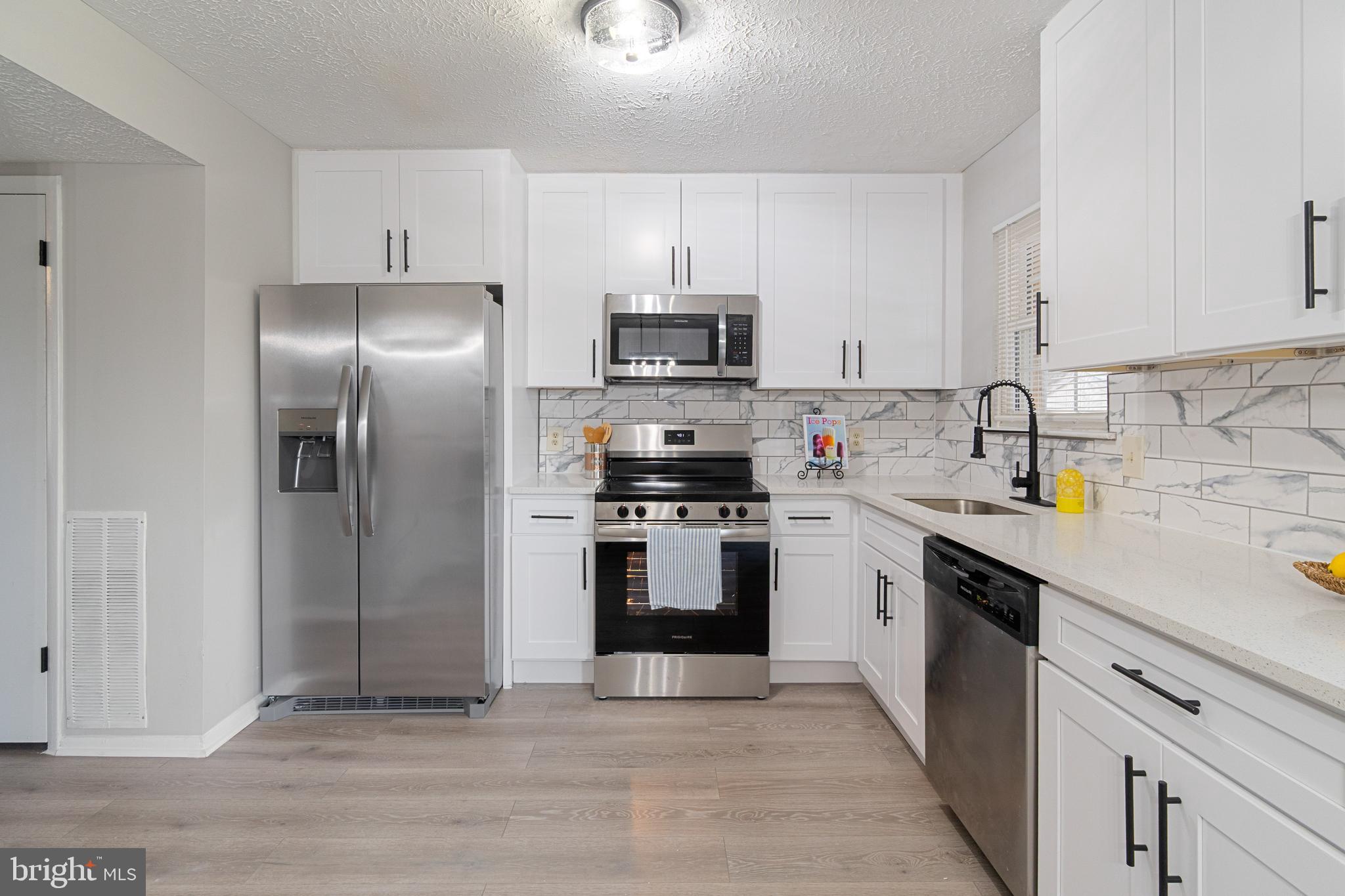 8546 Skipjack Place Pasadena, MD 21122 - Photo 5 of 20 a kitchen with granite countertop a refrigerator and a sink