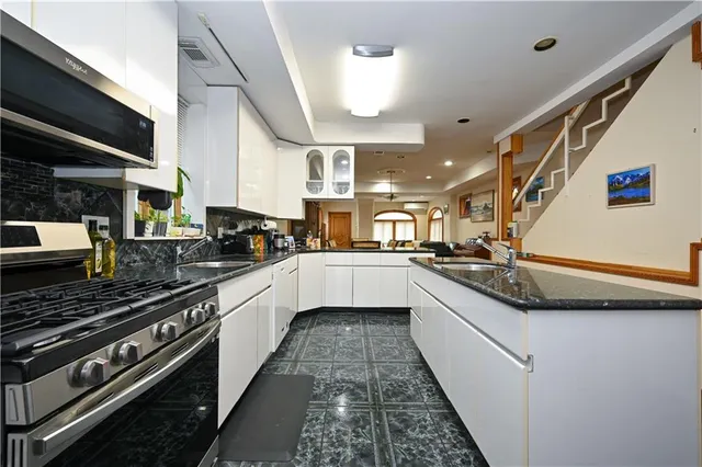 a large white kitchen with stainless steel appliances granite countertop a stove and a sink